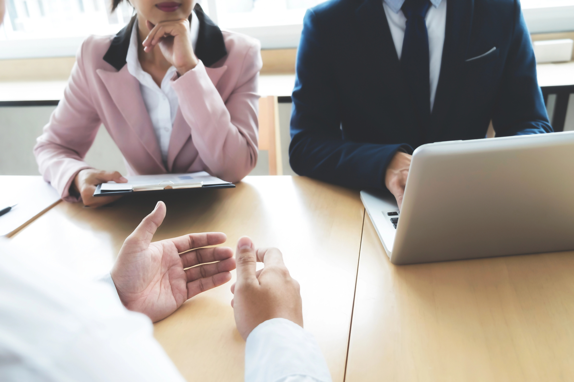 Spotkanie biznesowe, na którym omawiany jest bankowy tytuł egzekucyjny, trzech profesjonalistów przy stole z laptopem oraz dokumentami, rozmowa dotycząca kwestii finansowych i prawnych związanych z bankowym tytułem egzekucyjnym.