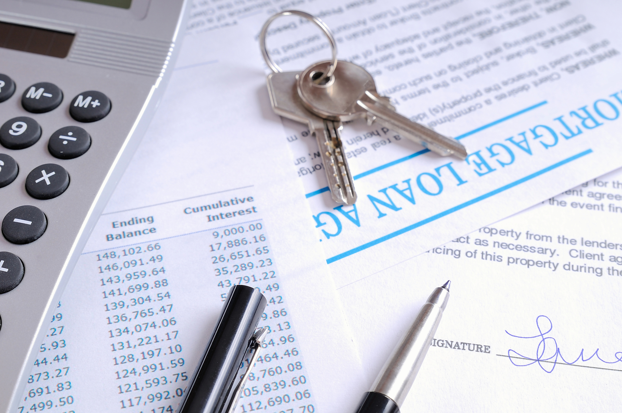 Dokumenty dotyczące kredytu hipotecznego, klucze do mieszkania, kalkulator i długopis na stole – nadpłata kredytu hipotecznego.