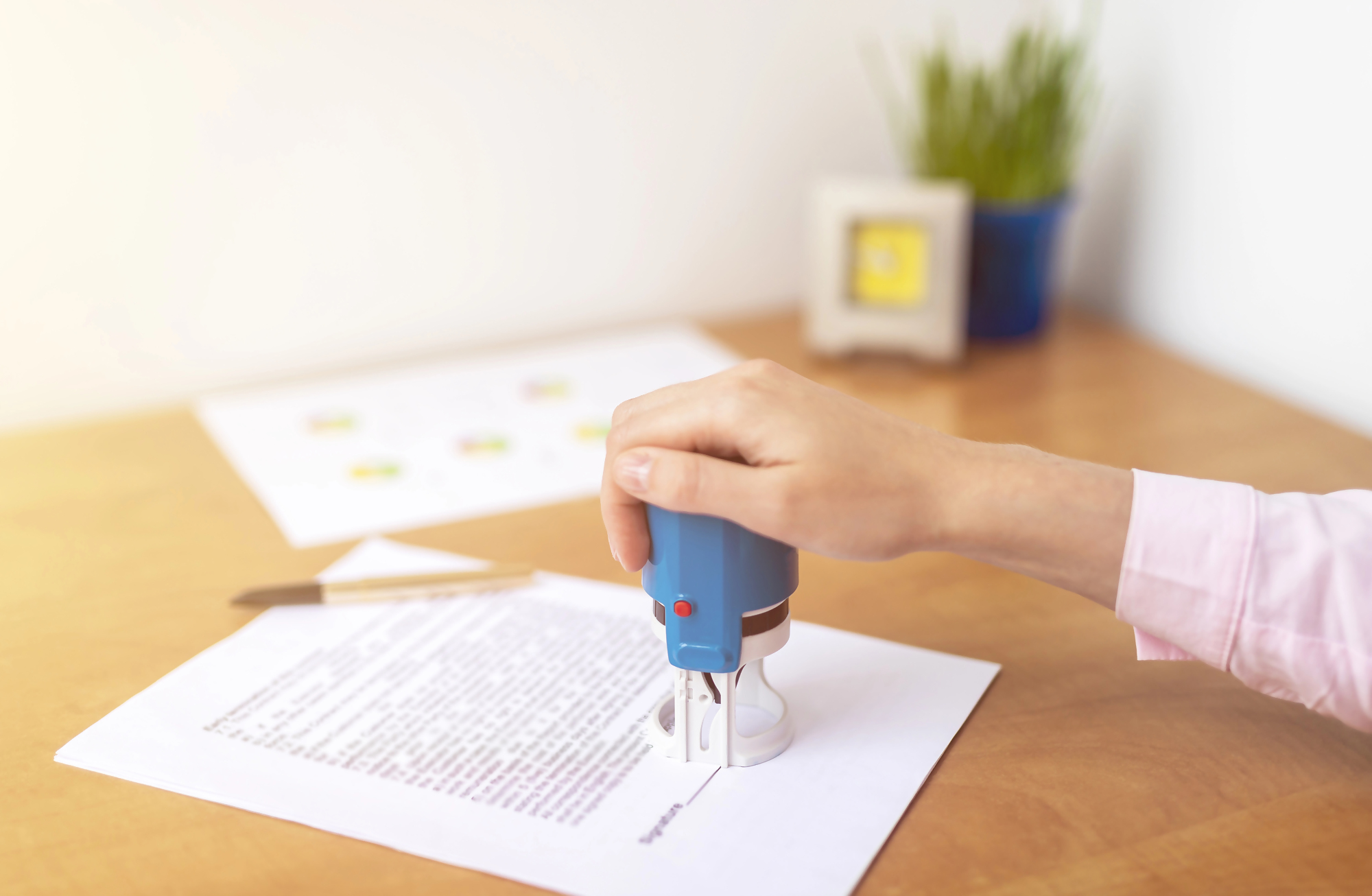 Sprzedaż mieszkania z kredytem – osoba stempluje ważny dokument związany z formalnościami sprzedaży nieruchomości obciążonej kredytem hipotecznym.