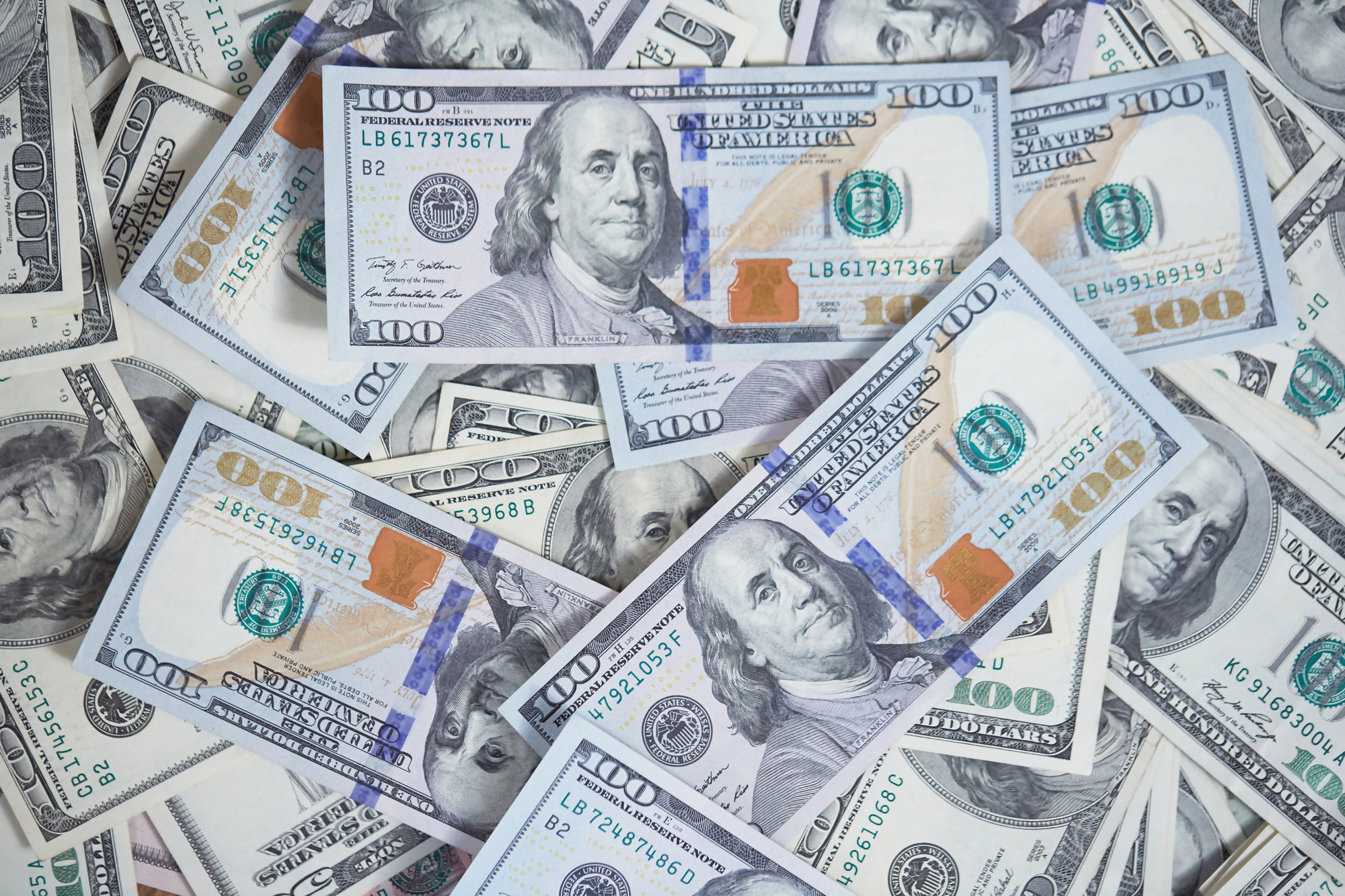 Obrazek przedstawiający rozrzucone amerykańskie banknoty, ilustrujący temat jak obniżyć ratę kredytu hipotecznego poprzez oszczędności i zarządzanie finansami.