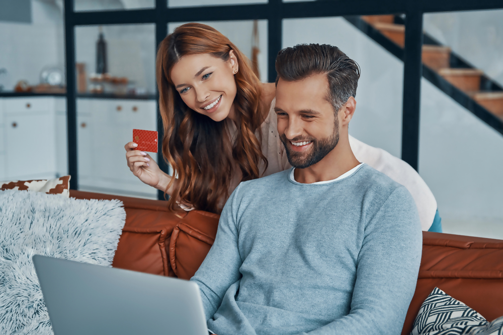 Osoby korzystające z bankowości internetowej na laptopie, ekran wyświetla panel konta online, zarządzanie finansami przez internet.