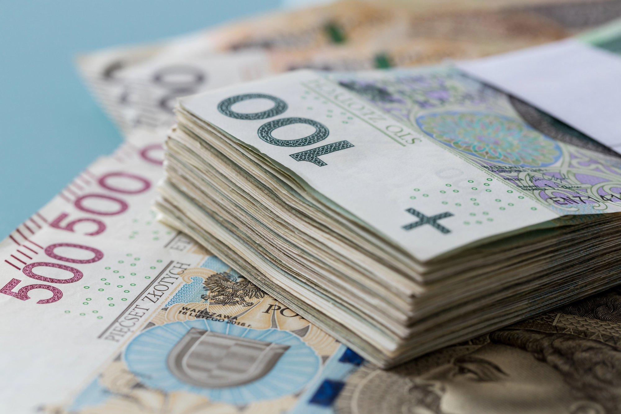 Stos polskich banknotów, w tym 100 i 500 złotych, przedstawiający temat wymiana zniszczonego banknotu w polskim systemie bankowym.