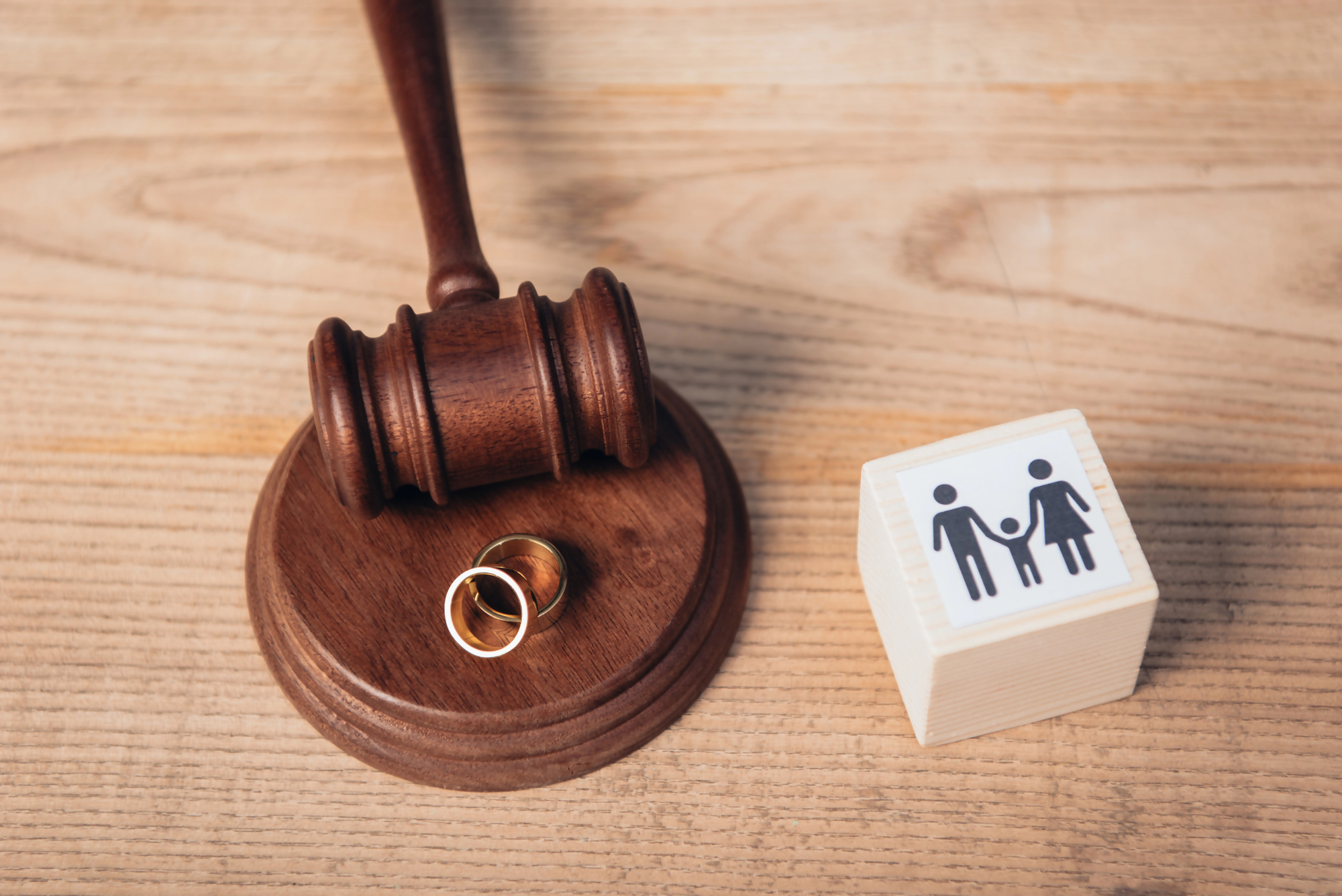 Rozdzielność majątkowa a kredyt – sędziowski młotek, obrączki oraz klocek z symbolem rodziny na drewnianym stole, ilustrujące wpływ rozdzielności majątkowej na kwestie kredytowe w małżeństwie.
