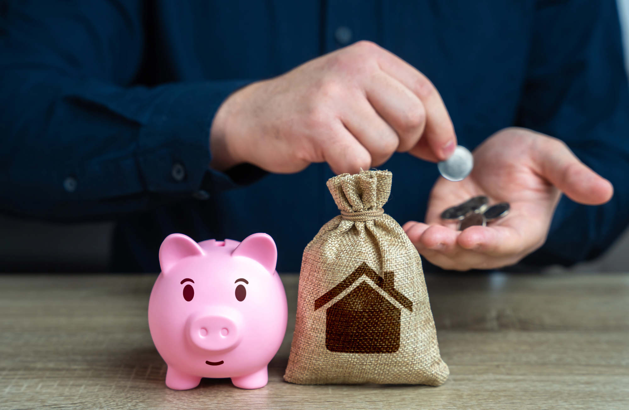 Rozdzielność majątkowa a kredyt – mężczyzna trzymający monety, obok różowa skarbonka i worek z symbolem domu, symbolizujące kwestie finansowe oraz kredyt hipoteczny przy rozdzielności majątkowej.