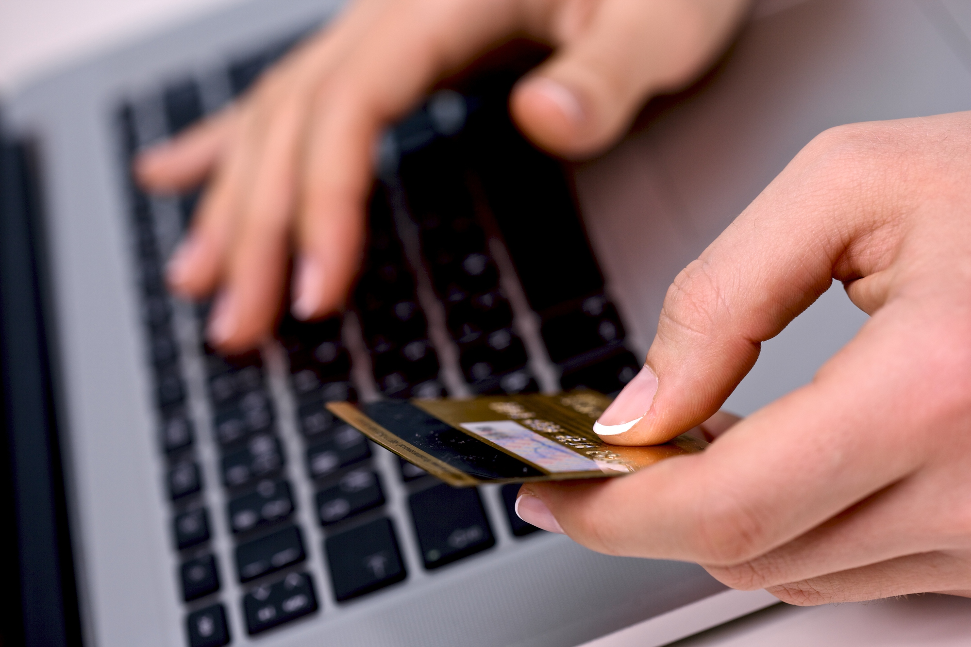 Osoba trzymająca kartę płatniczą i wpisująca dane na laptopie, ilustracja do artykułu czym jest inflacja oraz jak inflacja wpływa na codzienne zakupy i płatności online.