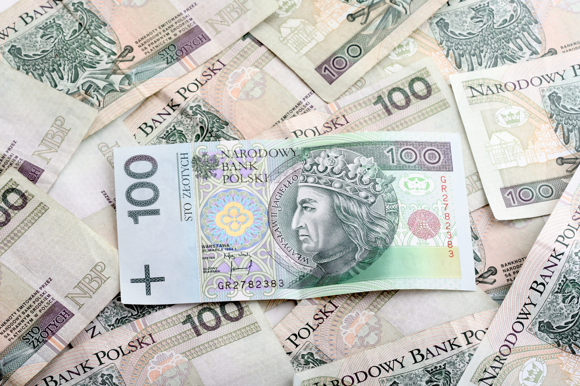 Czy warto trzymać oszczędności w euro – polskie banknoty 100 zł, symbolizujące rozważania o przechowywaniu oszczędności w złotówkach lub euro, kontekst inwestycji i zarządzania finansami.