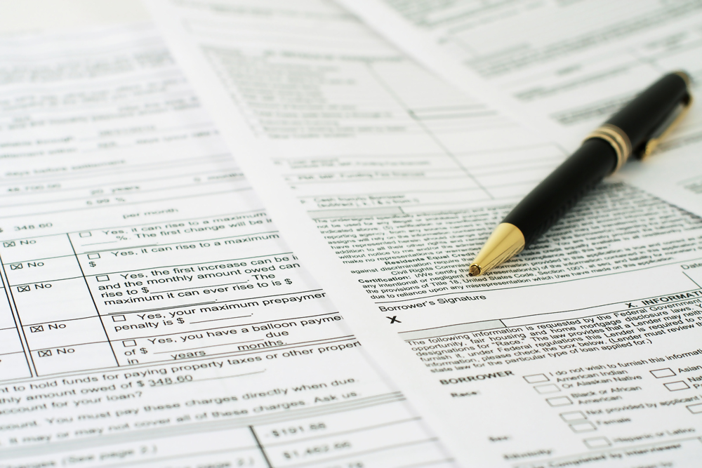 Dokumenty urzędowe i formularze podatkowe z długopisem, wypełnianie papierów finansowych.