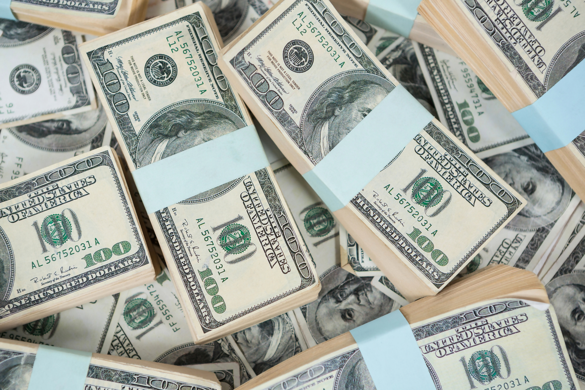 Stosy banknotów dolarowych przedstawiające tematykę "w jakiej walucie trzymać oszczędności" – na zdjęciu widoczne pliki stu dolarowych banknotów amerykańskich, co nawiązuje do wyboru odpowiedniej waluty do przechowywania oszczędności.