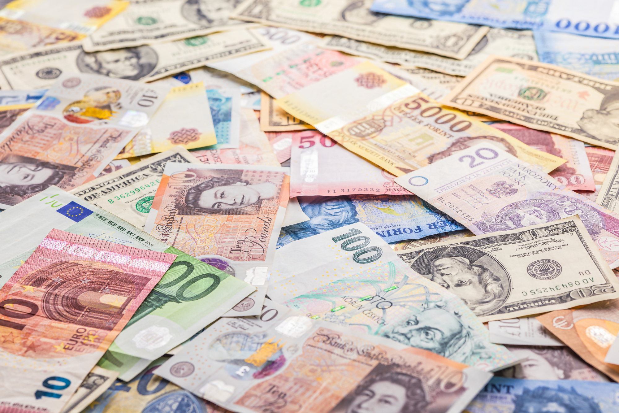 Różne banknoty walut światowych, takich jak dolar, euro, funt, frank i złoty, ukazujące temat deprecjacji wartości pieniędzy na rynku walutowym.