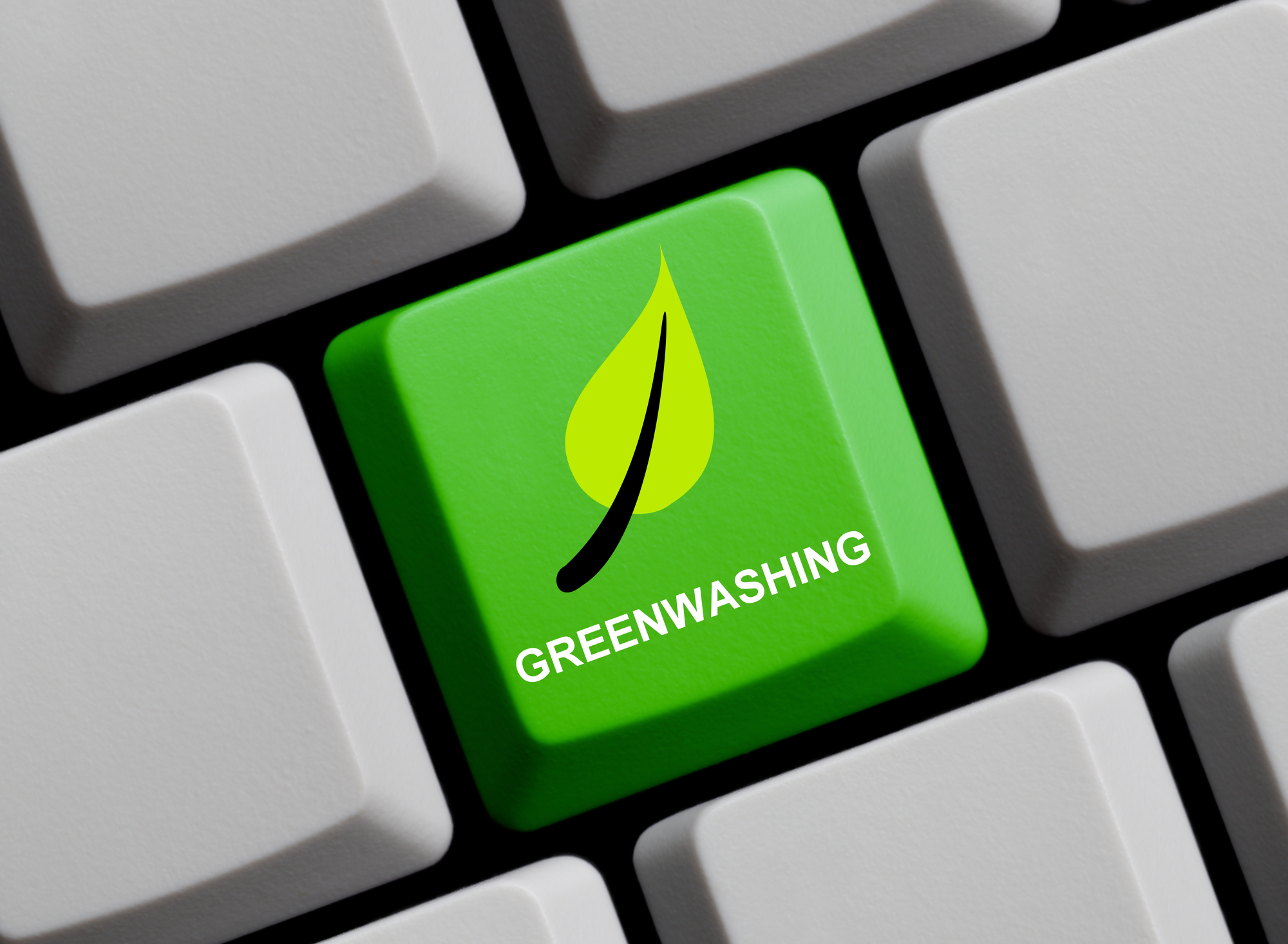 Zielony klawisz na klawiaturze z napisem "greenwashing" oraz symbolem liścia, ilustracja przedstawiająca temat greenwashingu i pozornego dbania o środowisko przez firmy, służąca do wizualizacji pojęcia greenwashing w kontekście SEO.
