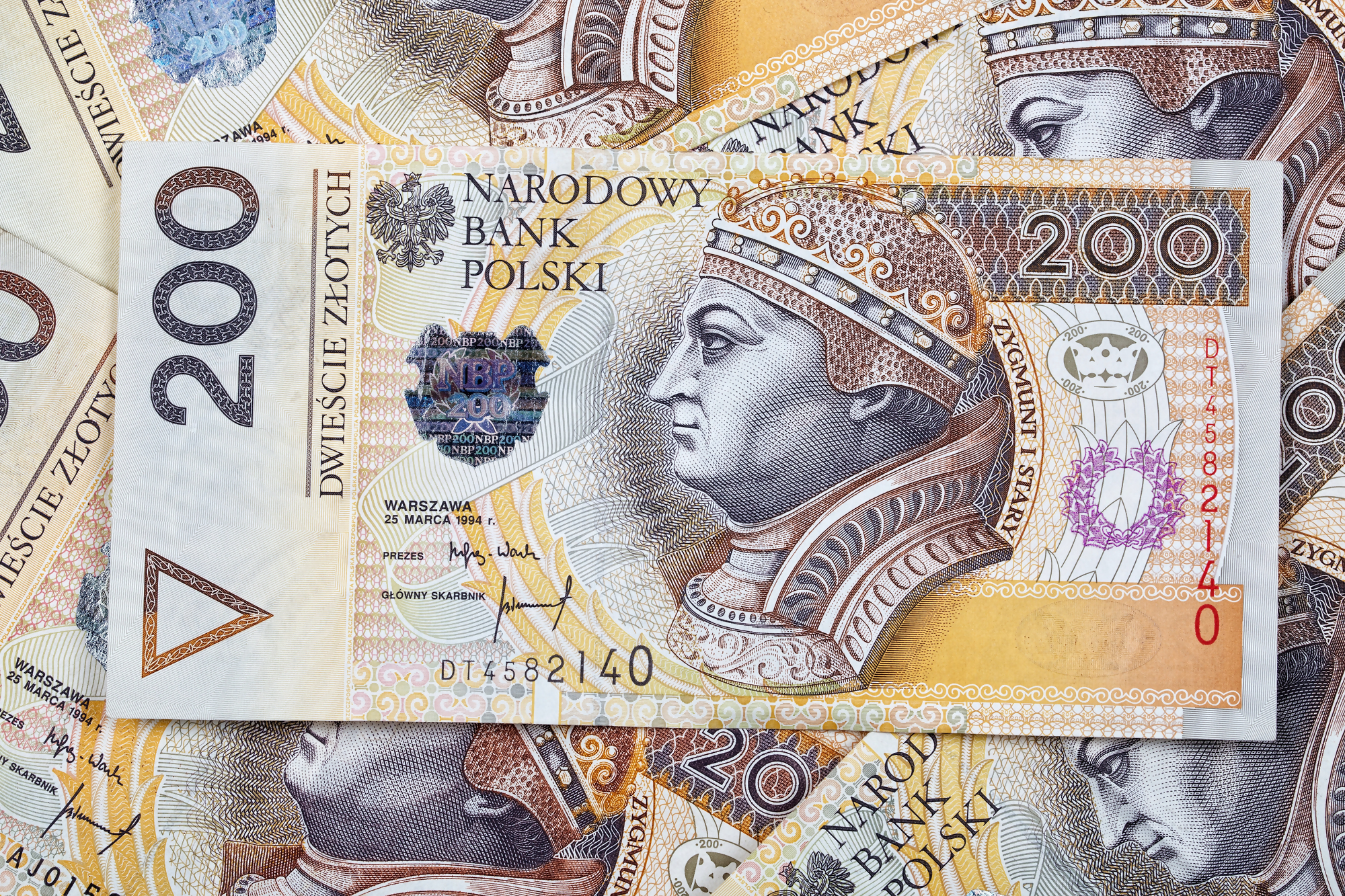 Polskie banknoty o nominale 200 złotych ułożone na sobie, przedstawiające temat inwestowania oraz finansowania, w tym obligacje korporacyjne jako alternatywę dla trzymania gotówki.