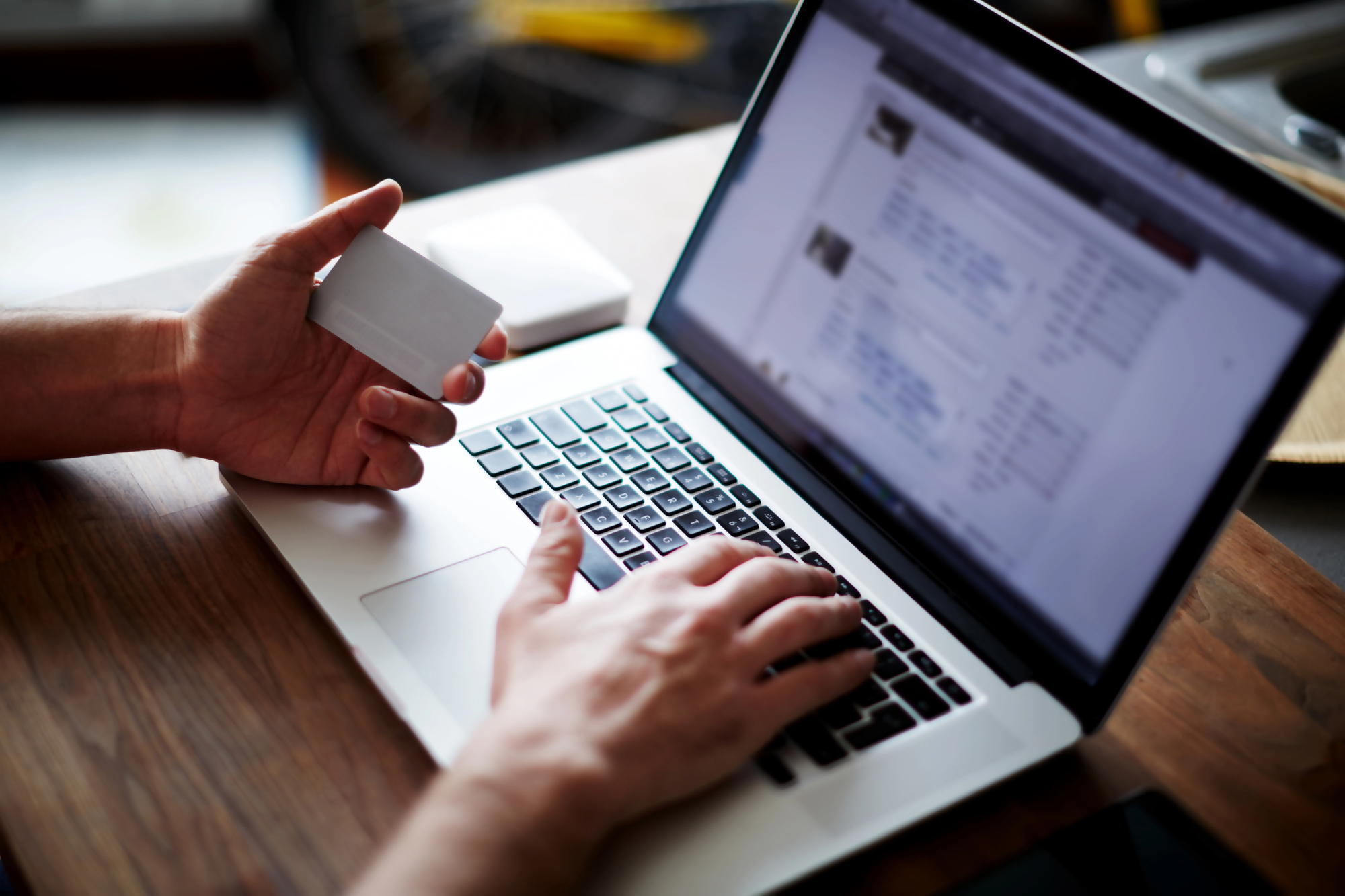 Osoba wpisująca numer IBAN podczas dokonywania płatności online za pomocą karty kredytowej przy laptopie.